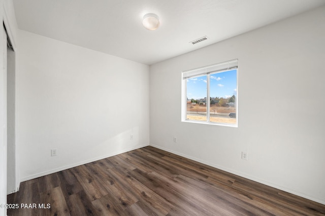 unfurnished room with visible vents, dark wood-type flooring, and baseboards