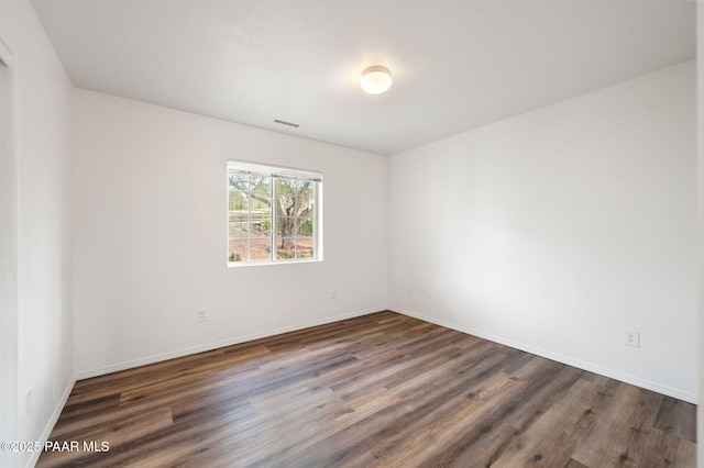 unfurnished room with visible vents, wood finished floors, and baseboards