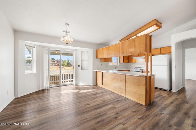 kitchen featuring white appliances, a peninsula, vaulted ceiling, and light countertops