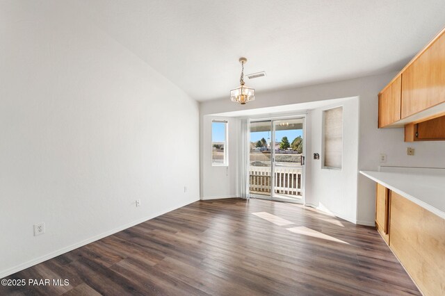 unfurnished dining area with dark wood-style floors, visible vents, baseboards, and an inviting chandelier