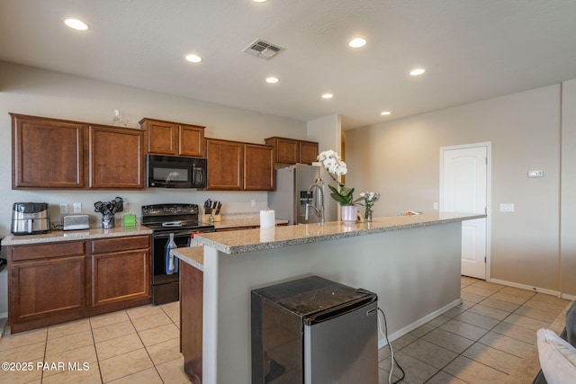 13109 E Gonzalez St, Dewey-Humboldt, AZ 86327 - kitchen with black appliances, light tile patterned floors, a center island with sink, recessed lighting, and brown cabinetry