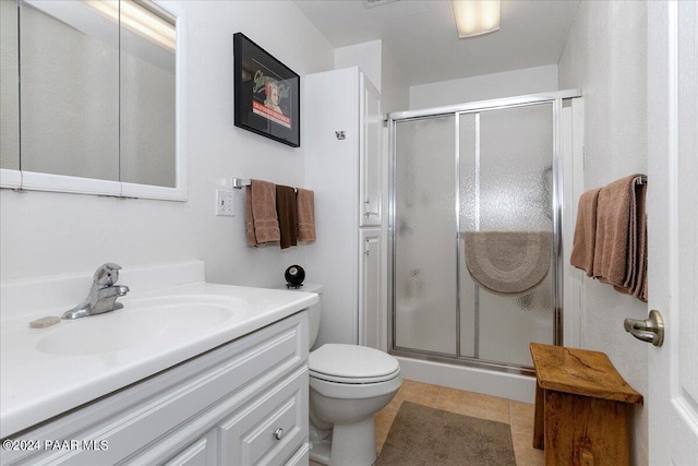 bathroom featuring toilet, vanity, tile patterned floors, and a shower with shower door