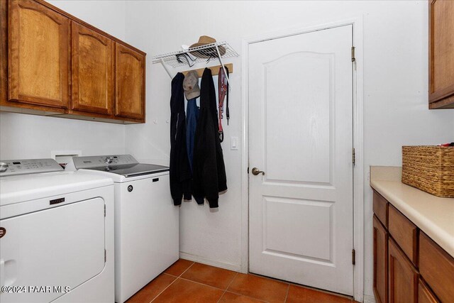 clothes washing area featuring washer and dryer, light tile patterned floors, and cabinets