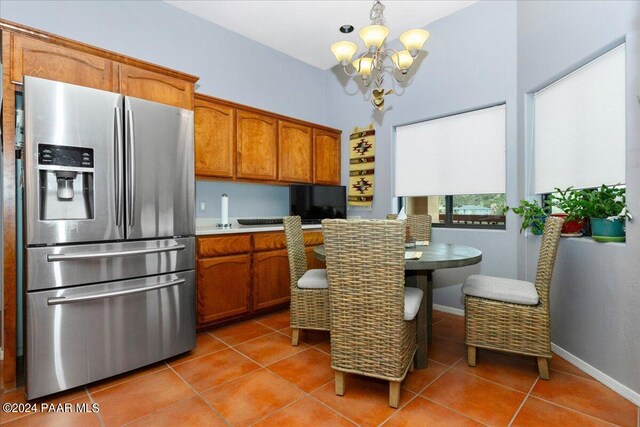 kitchen with tile patterned flooring, pendant lighting, stainless steel refrigerator with ice dispenser, and a notable chandelier