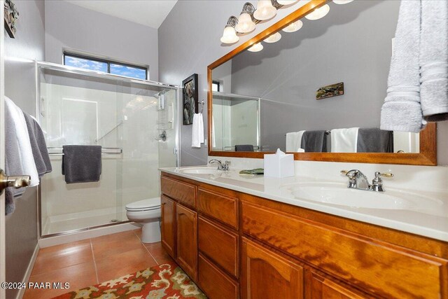 bathroom with tile patterned flooring, vanity, toilet, and a shower with door