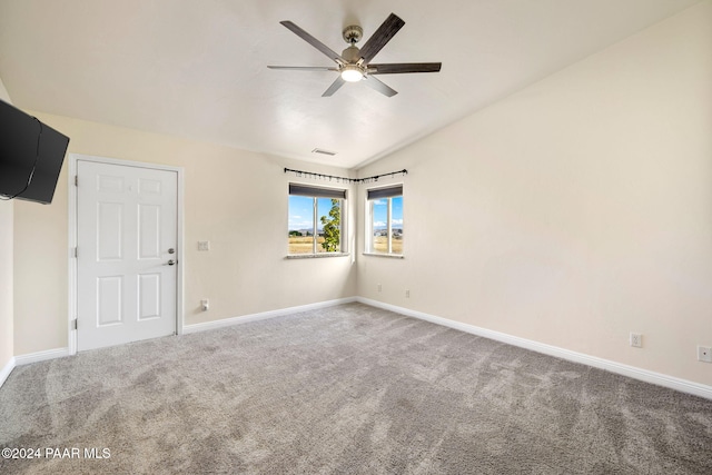 empty room with vaulted ceiling, carpet flooring, a ceiling fan, and baseboards