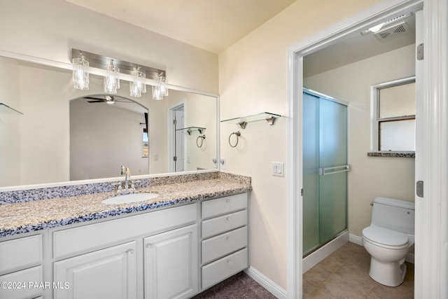 bathroom with ceiling fan, vanity, a shower with shower door, and toilet