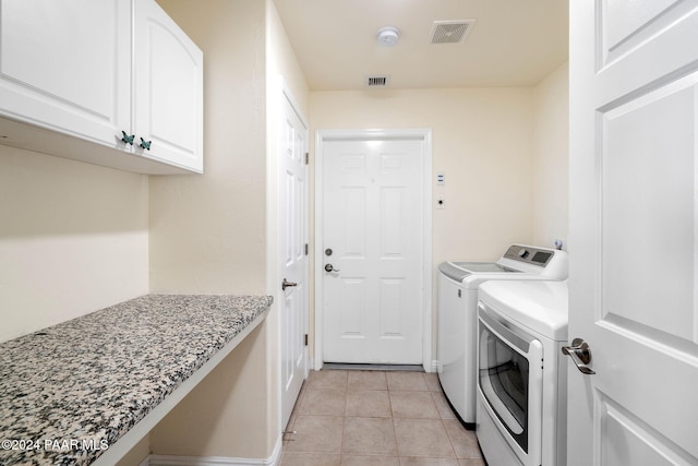 laundry room with cabinets, washing machine and dryer, and light tile patterned flooring