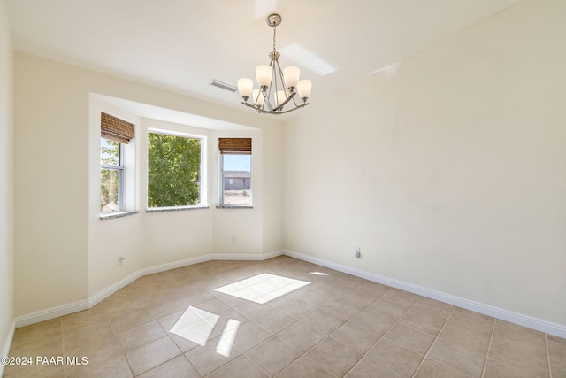 tiled spare room with a notable chandelier