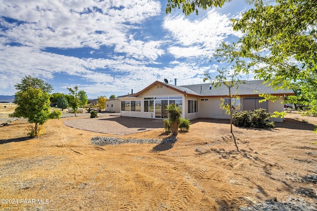 rear view of house featuring a sunroom and stucco siding