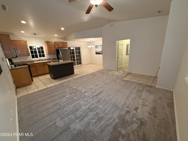 kitchen featuring a center island, lofted ceiling, light carpet, appliances with stainless steel finishes, and decorative light fixtures