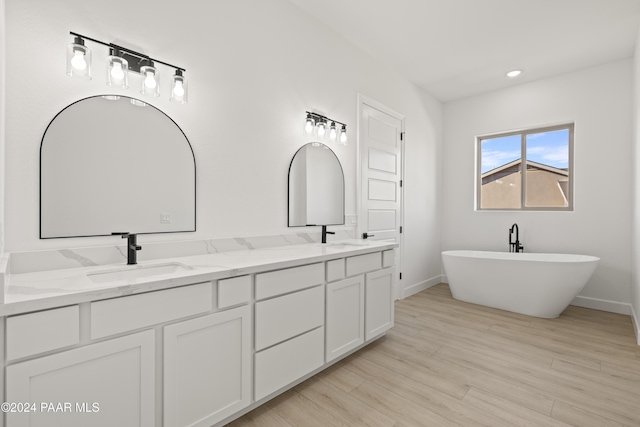 bathroom with a washtub, vanity, and hardwood / wood-style flooring