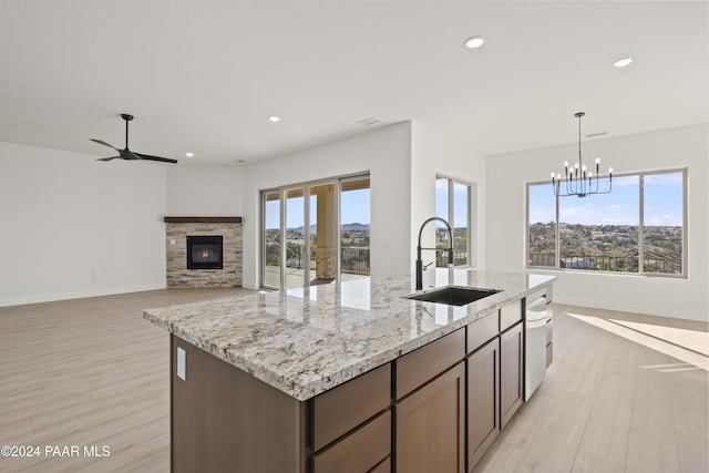 kitchen with a fireplace, light stone counters, sink, and light hardwood / wood-style floors