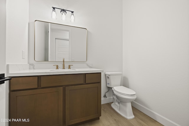 bathroom with wood-type flooring, vanity, and toilet