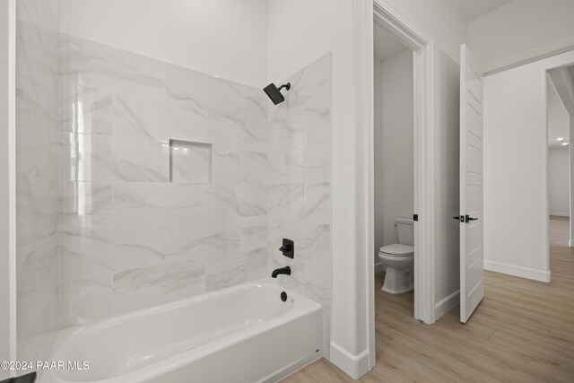 bathroom featuring hardwood / wood-style flooring, toilet, and tiled shower / bath