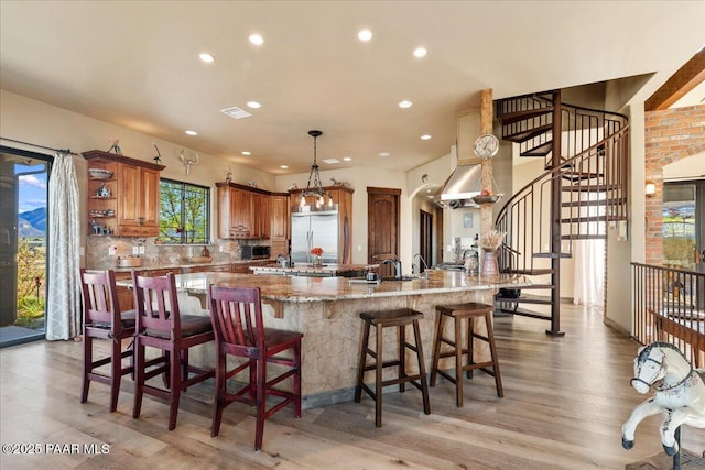 3825 W Wig Wag Way, Prescott, AZ 86305 - kitchen with a large island with sink, brown cabinetry, recessed lighting, built in fridge, and light wood-style floors
