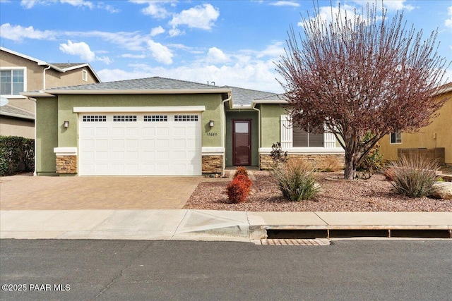 view of front of house featuring decorative driveway, stucco siding, an attached garage, and stone siding