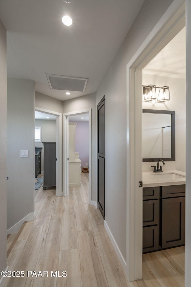 2905 S Omega Dr, Dewey-Humboldt, AZ 86329 - hallway featuring a sink, light wood-type flooring, and baseboards