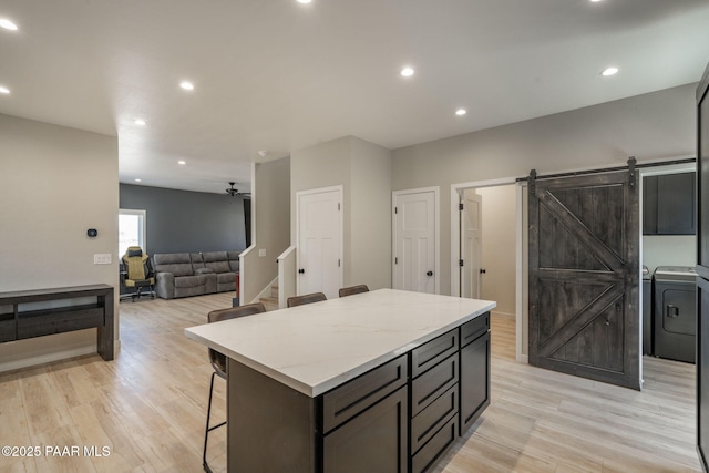 2905 S Omega Dr, Dewey-Humboldt, AZ 86329 - kitchen with washer / clothes dryer, a kitchen breakfast bar, light wood-style flooring, a kitchen island, and recessed lighting