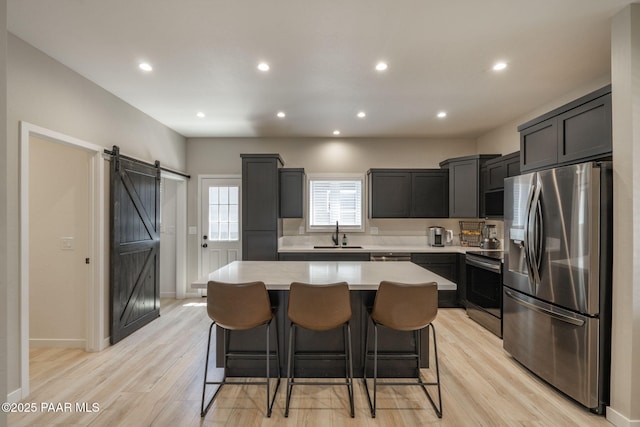 2905 S Omega Dr, Dewey-Humboldt, AZ 86329 - kitchen featuring appliances with stainless steel finishes, a barn door, a kitchen island, light countertops, and a kitchen breakfast bar