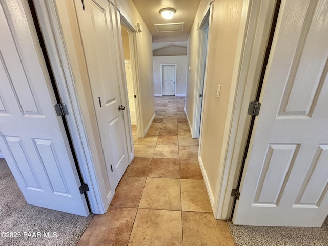 hall featuring light tile patterned floors, visible vents, attic access, and baseboards