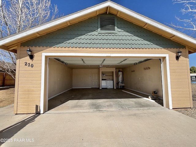 garage featuring washing machine and dryer, driveway, and gas water heater