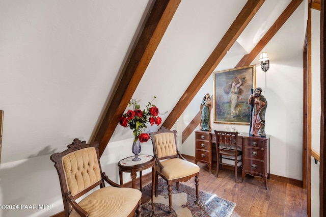 living area with hardwood / wood-style floors, vaulted ceiling with beams, and baseboards