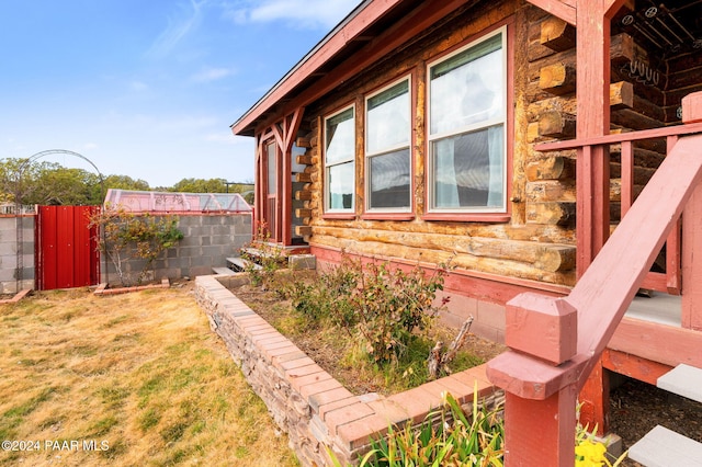 view of home's exterior featuring log exterior and fence