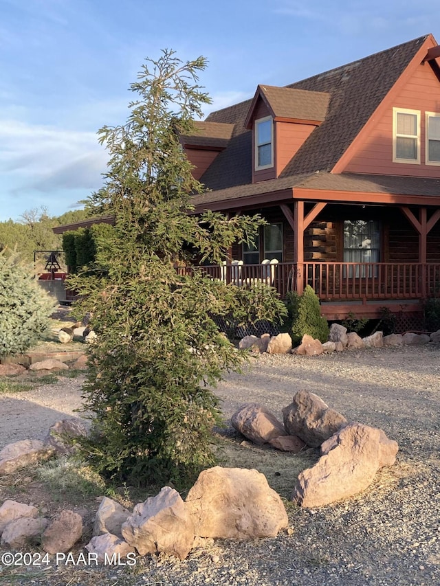 view of home's exterior with a porch and a shingled roof