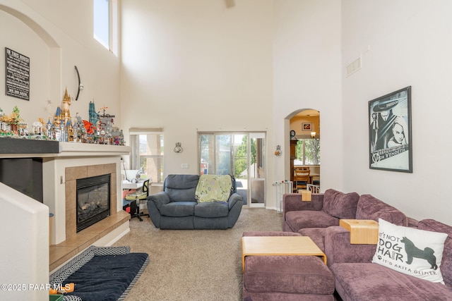 248 Lakewood Cv, Prescott, AZ 86301 - carpeted living area featuring a towering ceiling, a tiled fireplace, and arched walkways