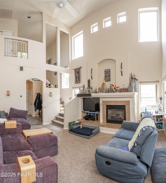 248 Lakewood Cv, Prescott, AZ 86301 - carpeted living room featuring a towering ceiling, a ceiling fan, arched walkways, a fireplace, and stairs