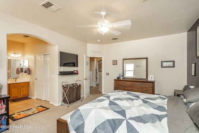 248 Lakewood Cv, Prescott, AZ 86301 - bedroom featuring arched walkways, light carpet, a closet, connected bathroom, and light tile patterned floors