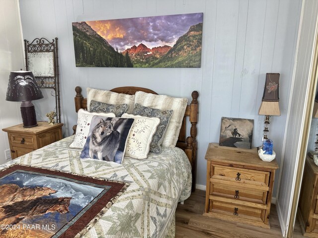 bedroom with hardwood / wood-style flooring and wood walls