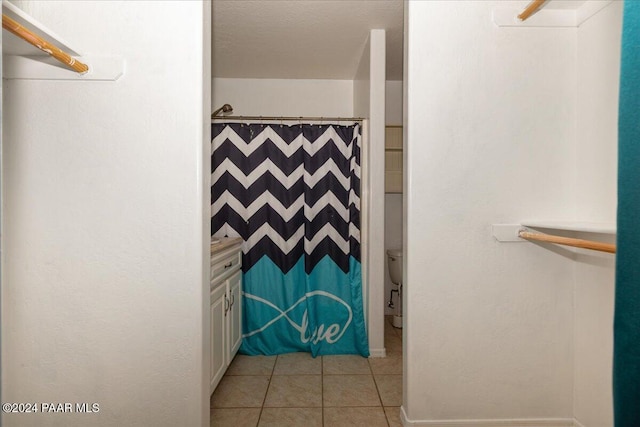 bathroom with tile patterned flooring, a textured ceiling, a shower with shower curtain, and toilet