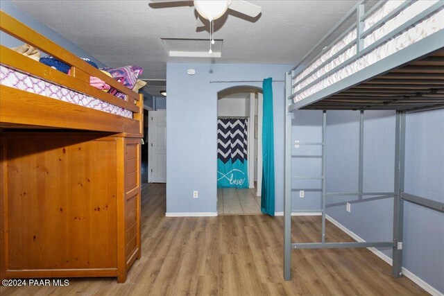 unfurnished bedroom featuring ceiling fan, a textured ceiling, and hardwood / wood-style flooring