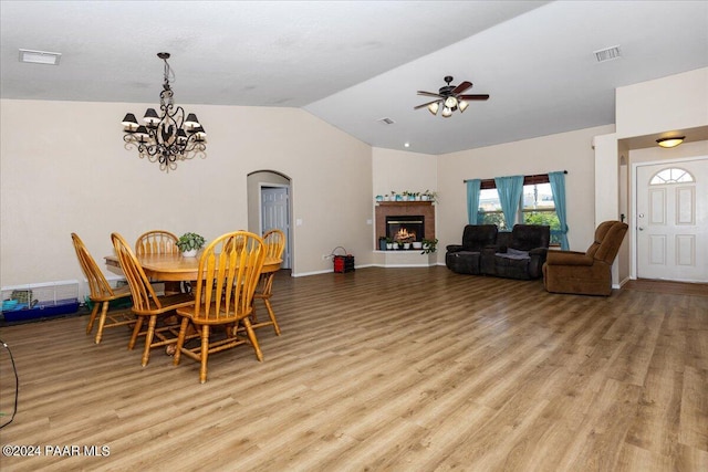 dining space with ceiling fan with notable chandelier, vaulted ceiling, and light hardwood / wood-style flooring