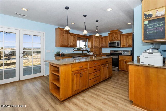 kitchen featuring a center island with sink, decorative light fixtures, plenty of natural light, and appliances with stainless steel finishes