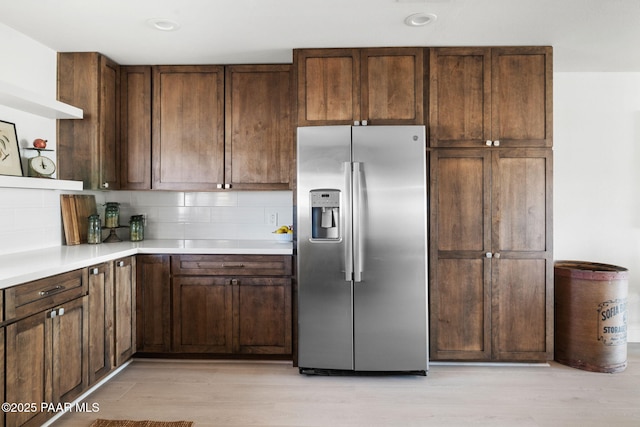 kitchen with tasteful backsplash, dark brown cabinets, light wood-type flooring, and stainless steel refrigerator with ice dispenser