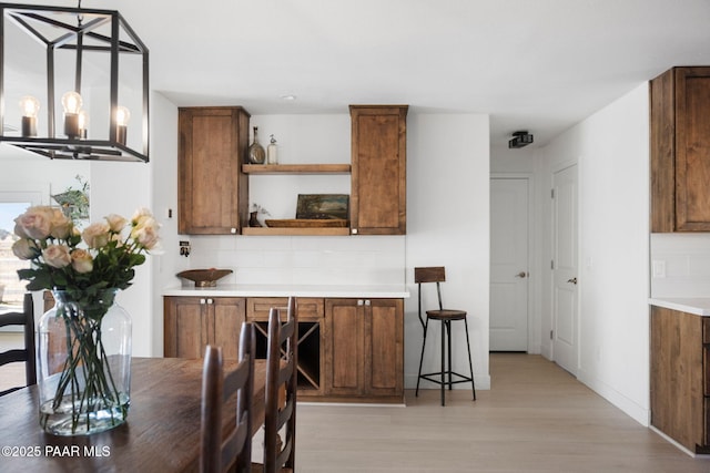 kitchen featuring hanging light fixtures, an inviting chandelier, light hardwood / wood-style floors, and decorative backsplash