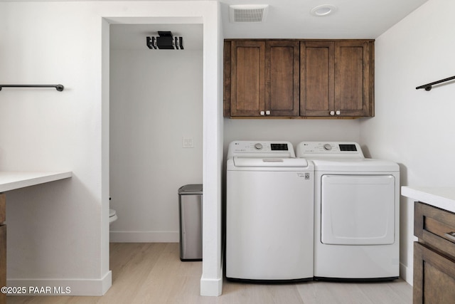 laundry area featuring cabinets, separate washer and dryer, and light hardwood / wood-style floors