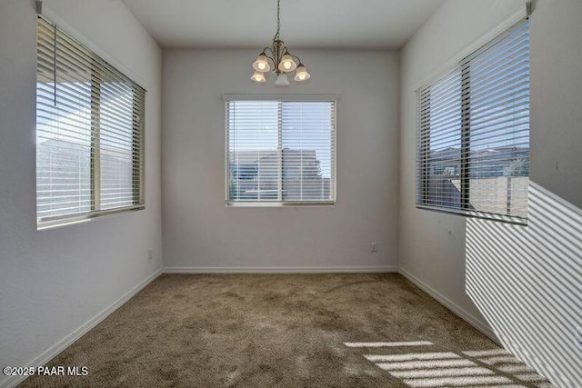 carpeted empty room featuring an inviting chandelier