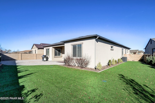 rear view of property featuring a patio, central air condition unit, and a lawn