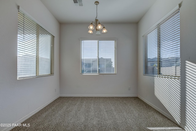 carpeted empty room featuring a chandelier