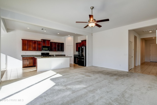 kitchen featuring light carpet, ceiling fan, black appliances, and an island with sink