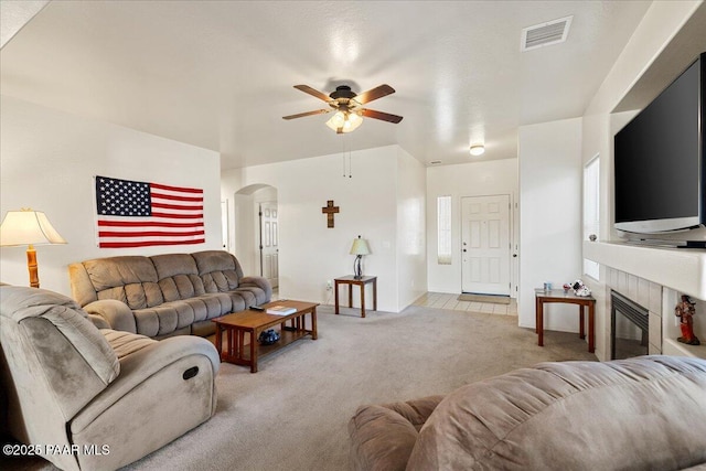 12912 E Santiago St, Dewey-Humboldt, AZ 86327 - living room with light carpet, a ceiling fan, arched walkways, and a tile fireplace