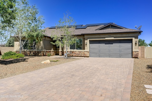 7506 E Roaring Canyon Rd, Prescott Valley, AZ 86315 - ranch-style house with stone siding, decorative driveway, stucco siding, roof mounted solar panels, and an attached garage