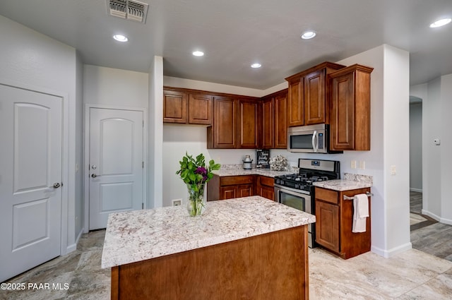 7506 E Roaring Canyon Rd, Prescott Valley, AZ 86315 - kitchen featuring stainless steel appliances, a center island, brown cabinetry, light stone counters, and recessed lighting