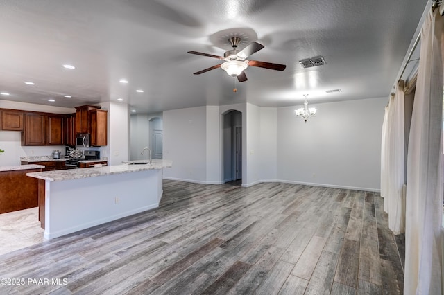 7506 E Roaring Canyon Rd, Prescott Valley, AZ 86315 - kitchen with arched walkways, appliances with stainless steel finishes, light wood-style floors, ceiling fan, and light stone countertops