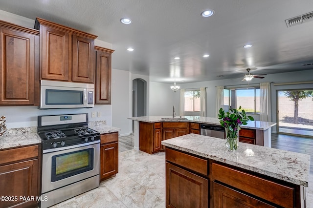 7506 E Roaring Canyon Rd, Prescott Valley, AZ 86315 - kitchen with stainless steel appliances, a kitchen island, arched walkways, plenty of natural light, and recessed lighting