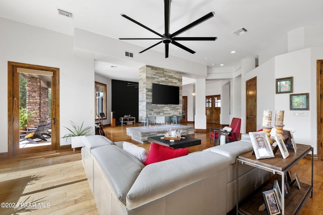 living room featuring a fireplace, light hardwood / wood-style flooring, and ceiling fan